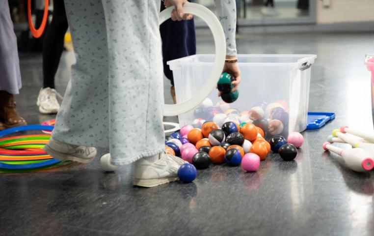 Student reaching in a bin of juggling balls