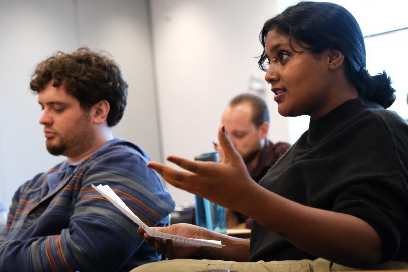 Philosophy students seated in discussion as Nanda Harish leads the conversation, gesturing with papers in hand.